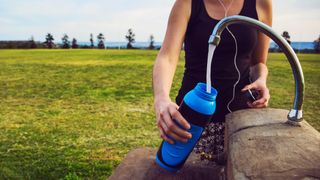 Woman refilling water bottle during a run