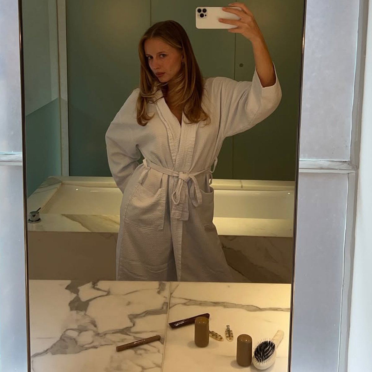 Hannah Juneva taking a mirror selfie in a bath robe.