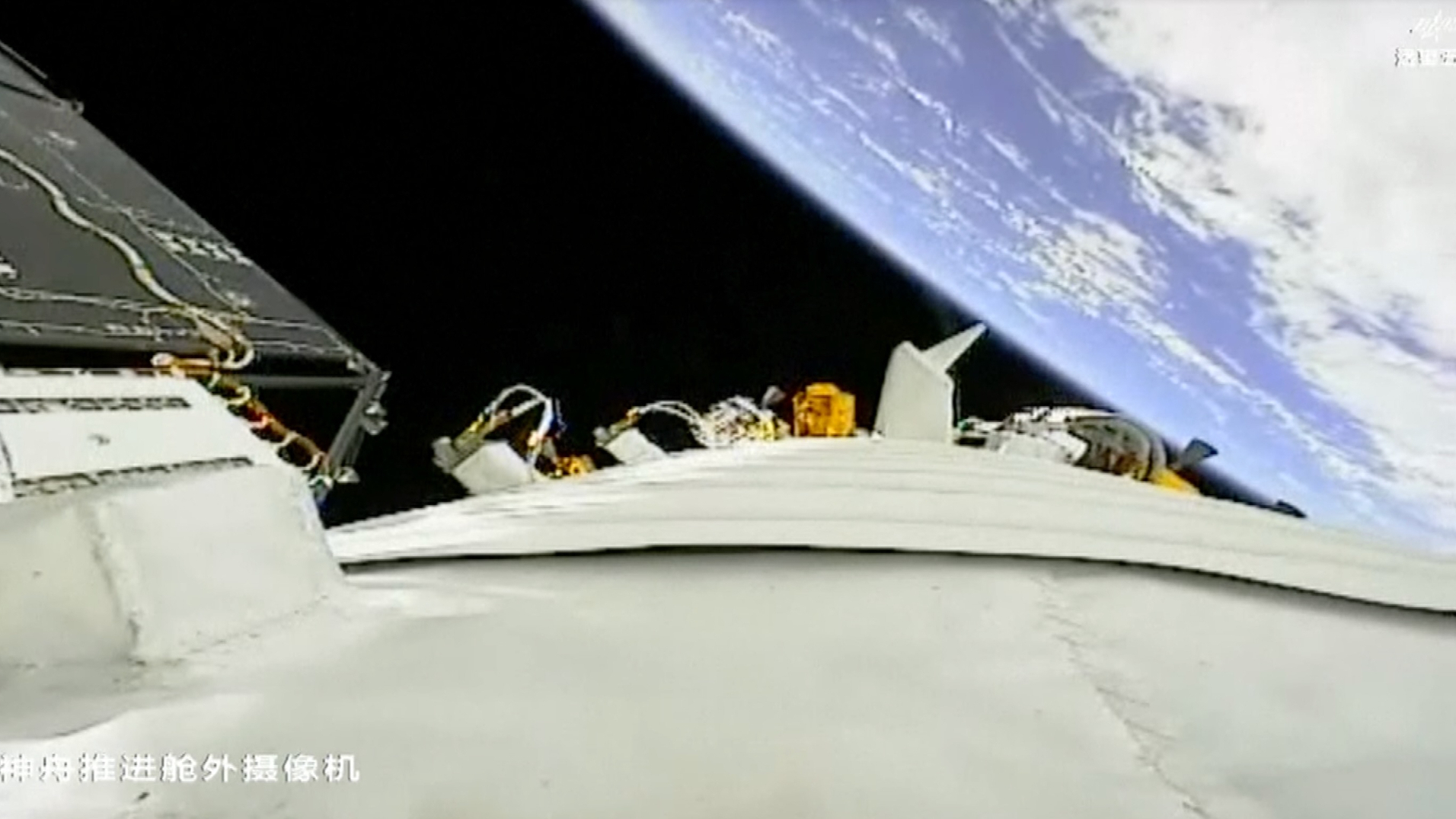 view from an orbiting spacecraft looking down at earth, with parts of the spacecraft in the foreground