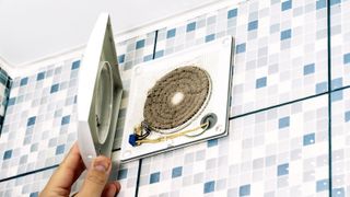 Open bathroom extractor fan on blue mosaic tiles