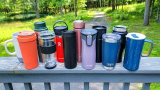 The best travel coffee mugs displayed together on an outdoor railing