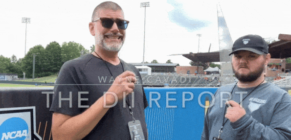 Wayne Cavadi stands with Robert Frey conducting an interview on a baseball field.
