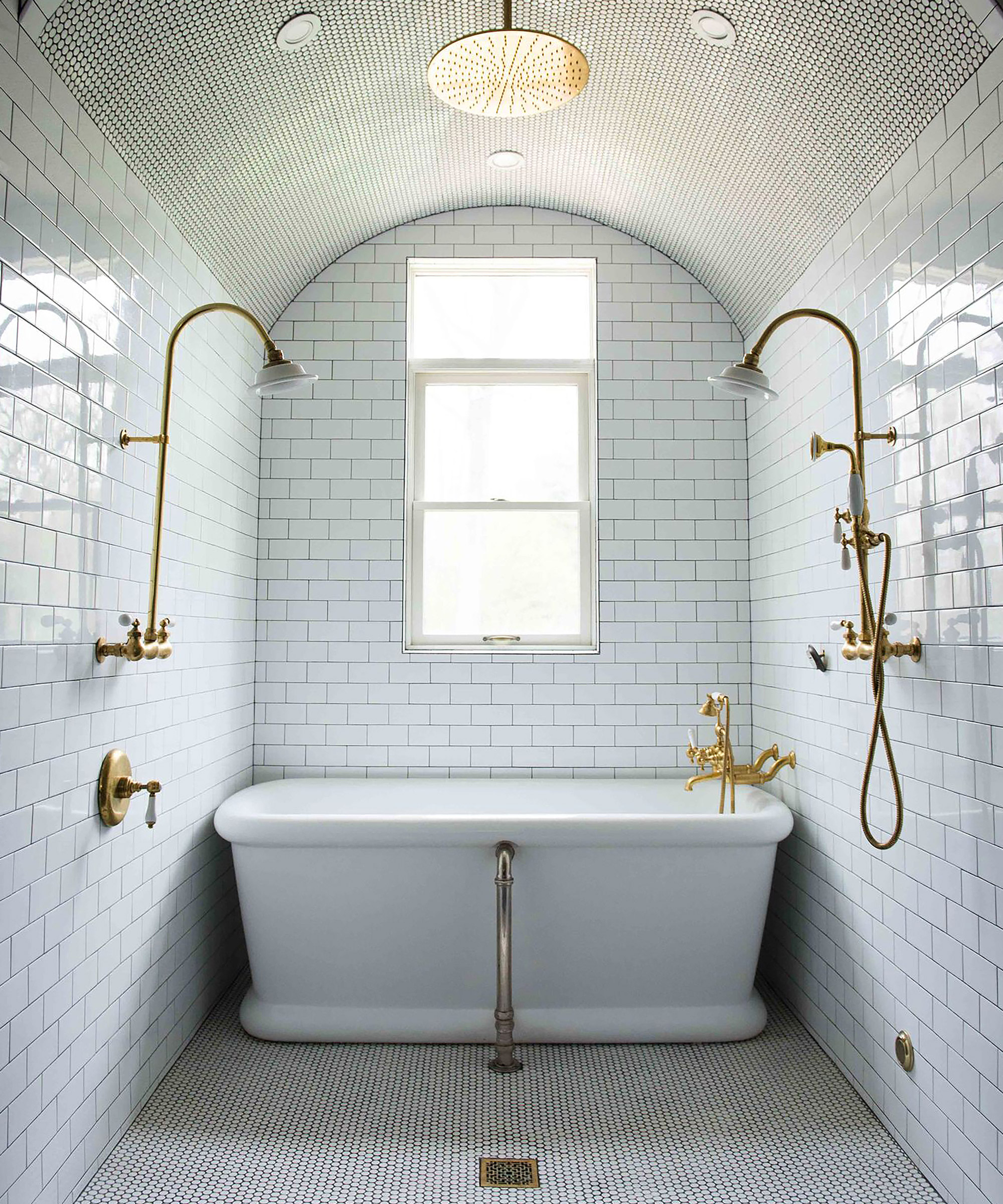 An example of small bathroom ideas showing two gold shower faucets over a white bath