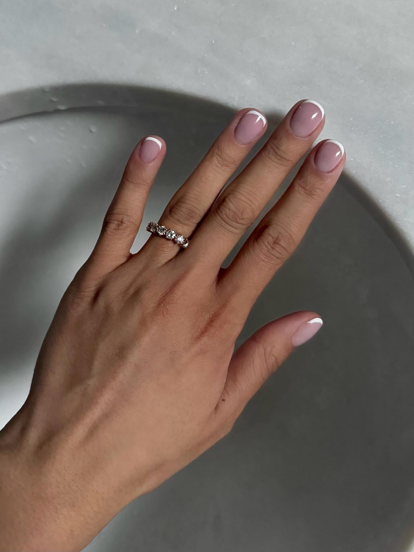 A short round manicure with a classic pink base and white French tips