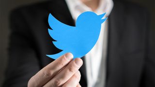 A man in a business suit holding the Twitter logo