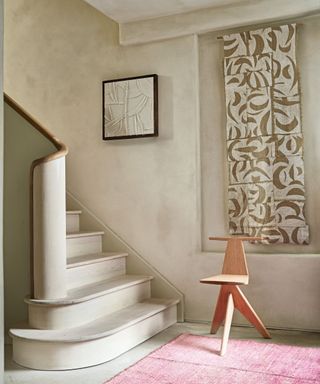 Pink rug, grey walls and staircase, wall hanging