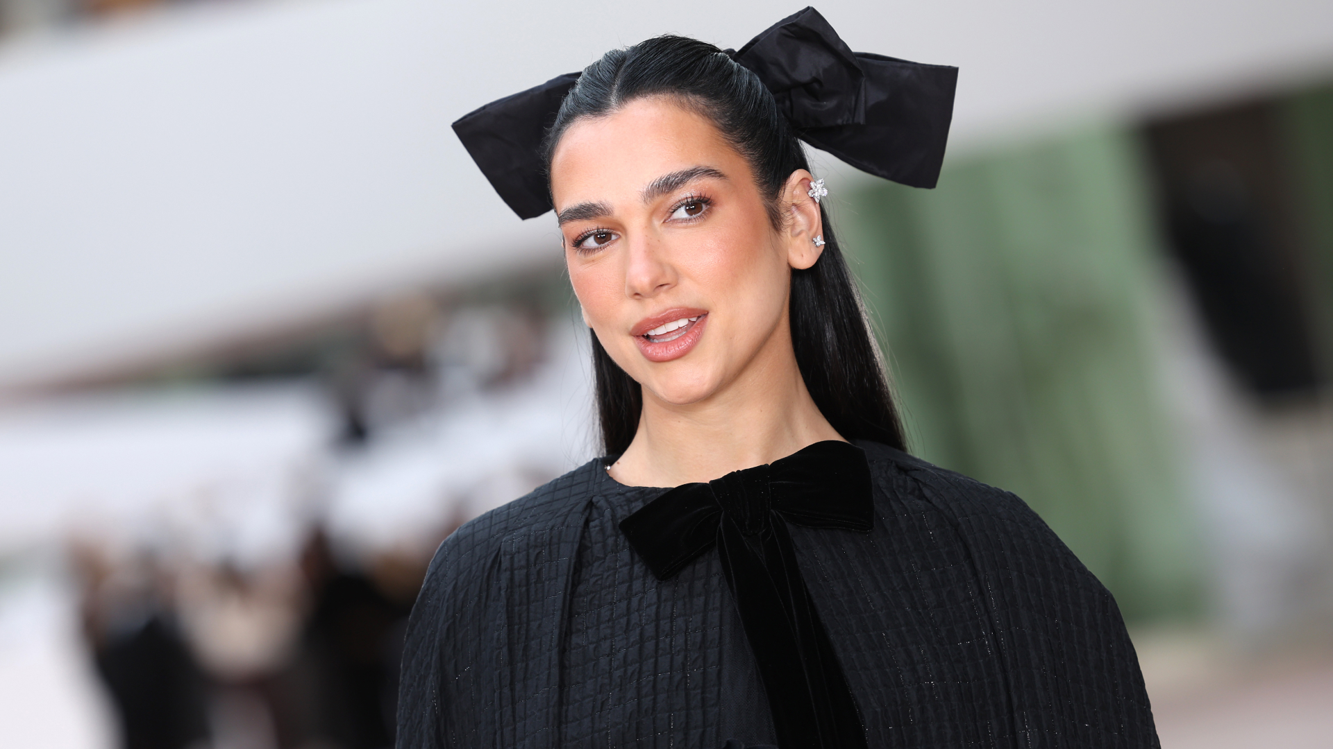 Dua Lipa on a red carpet wearing a bow