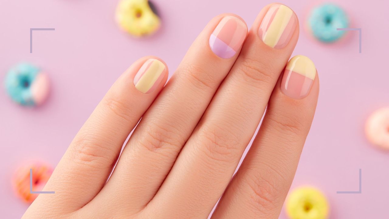 A woman&#039;s hand with pastel nails and negative space manicure with fruit loops 