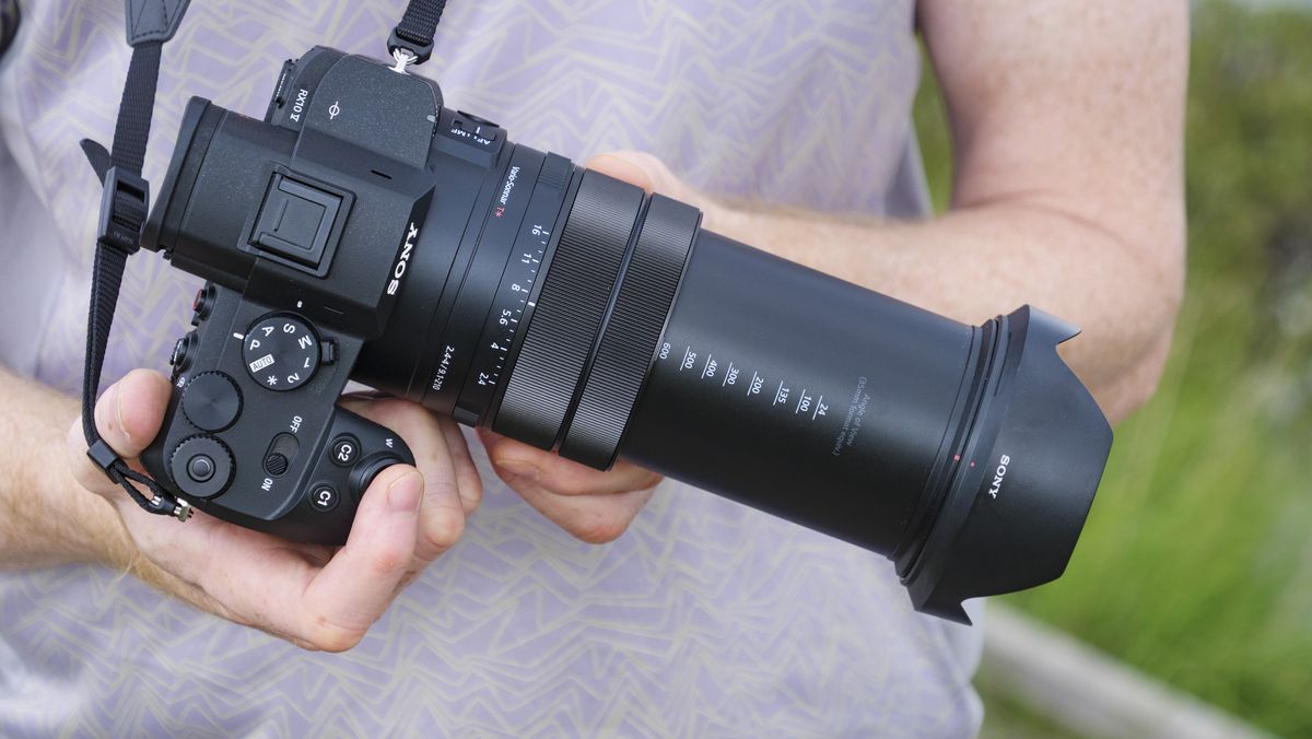 Photographer and tech journalist Tim Coleman holding the Sony RX10 V bridge camera, its lens is zoomed out