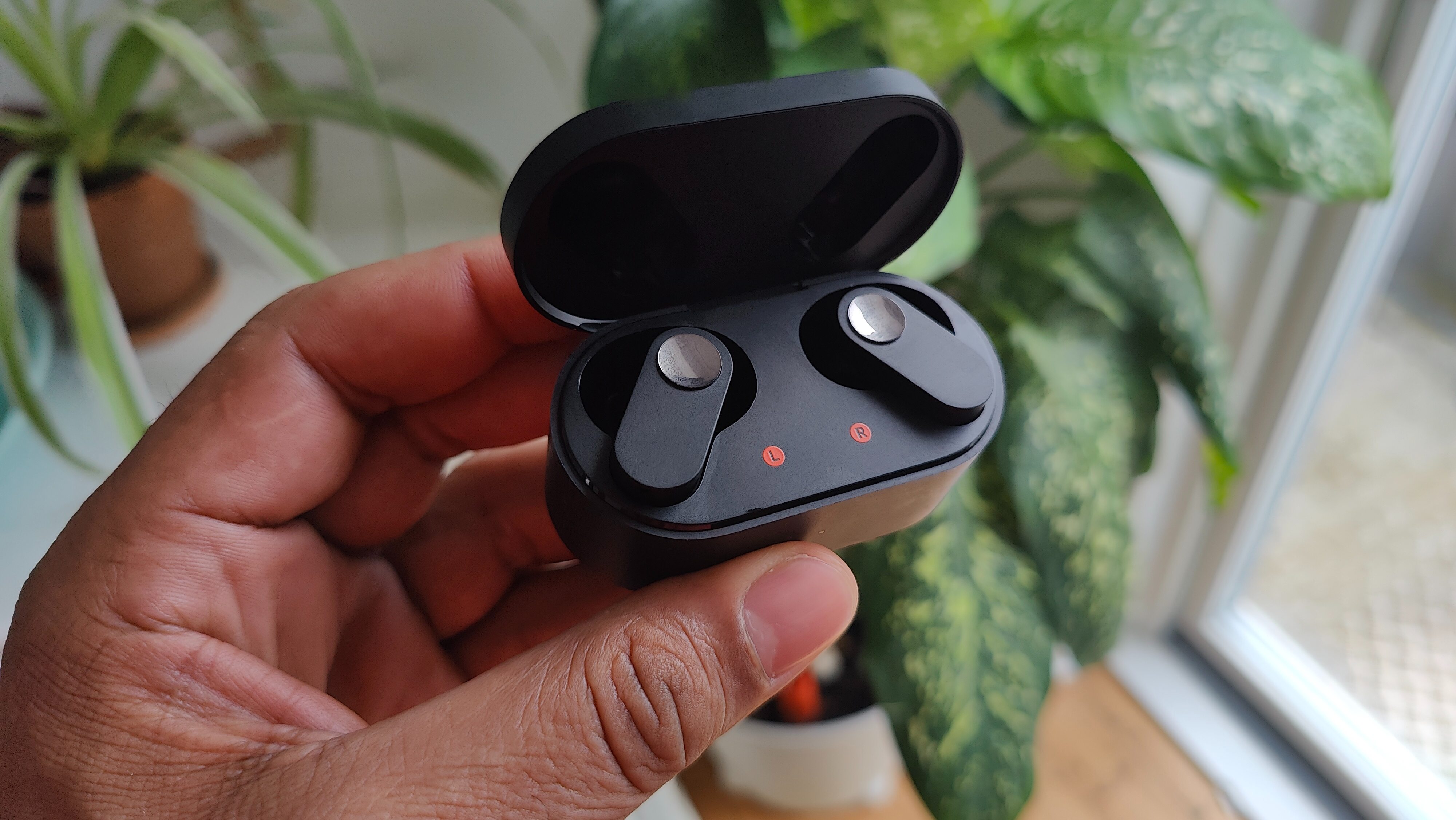 En hand håller i laddningsfodralet med två OnePlus Nord Buds