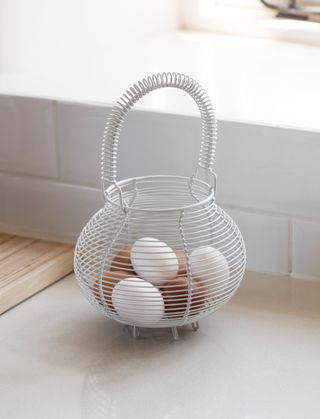 Fresh eggs stored in an egg basket on a kitchen worksurface
