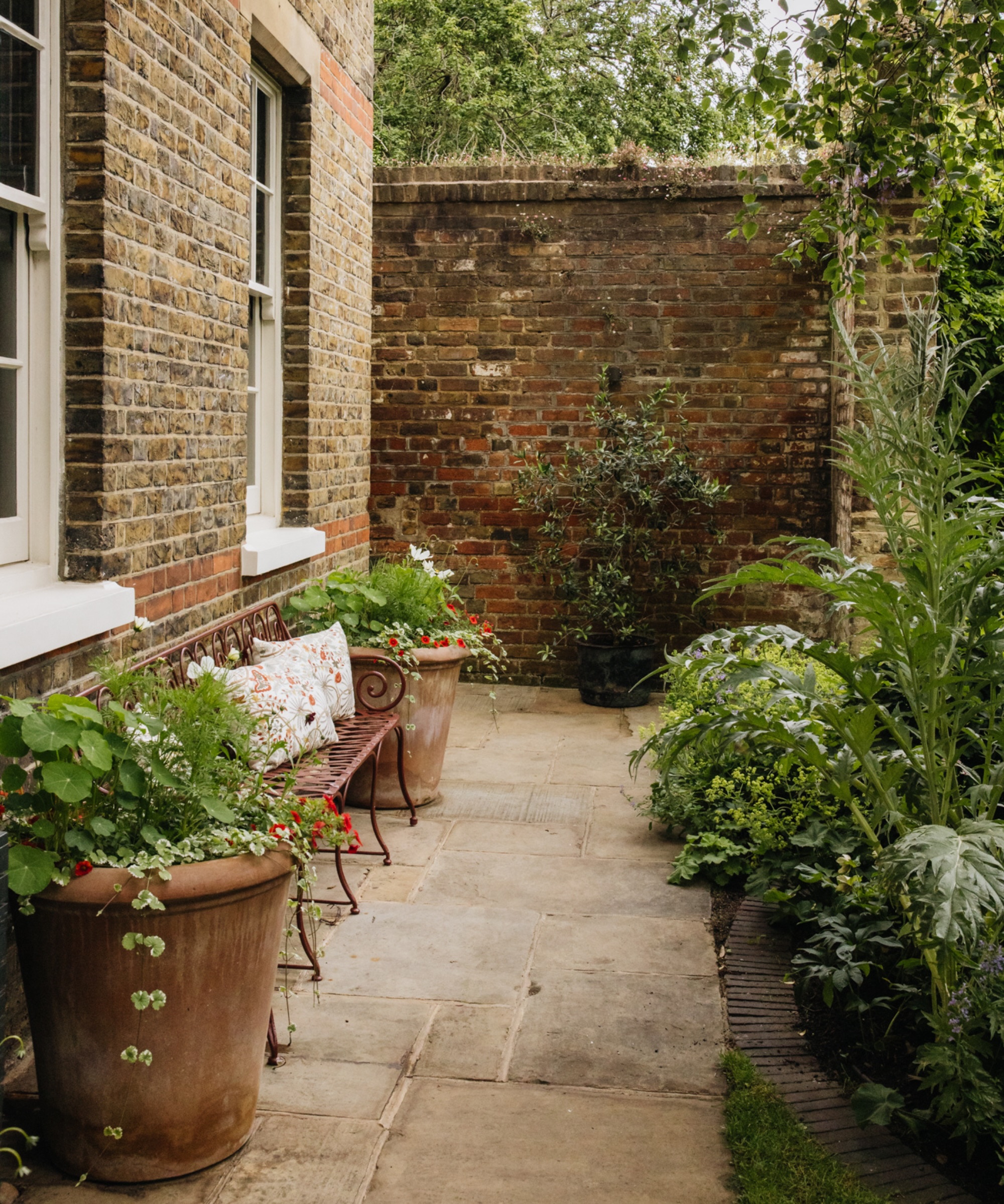 Vintage style garden with terracotta pots and metal bench