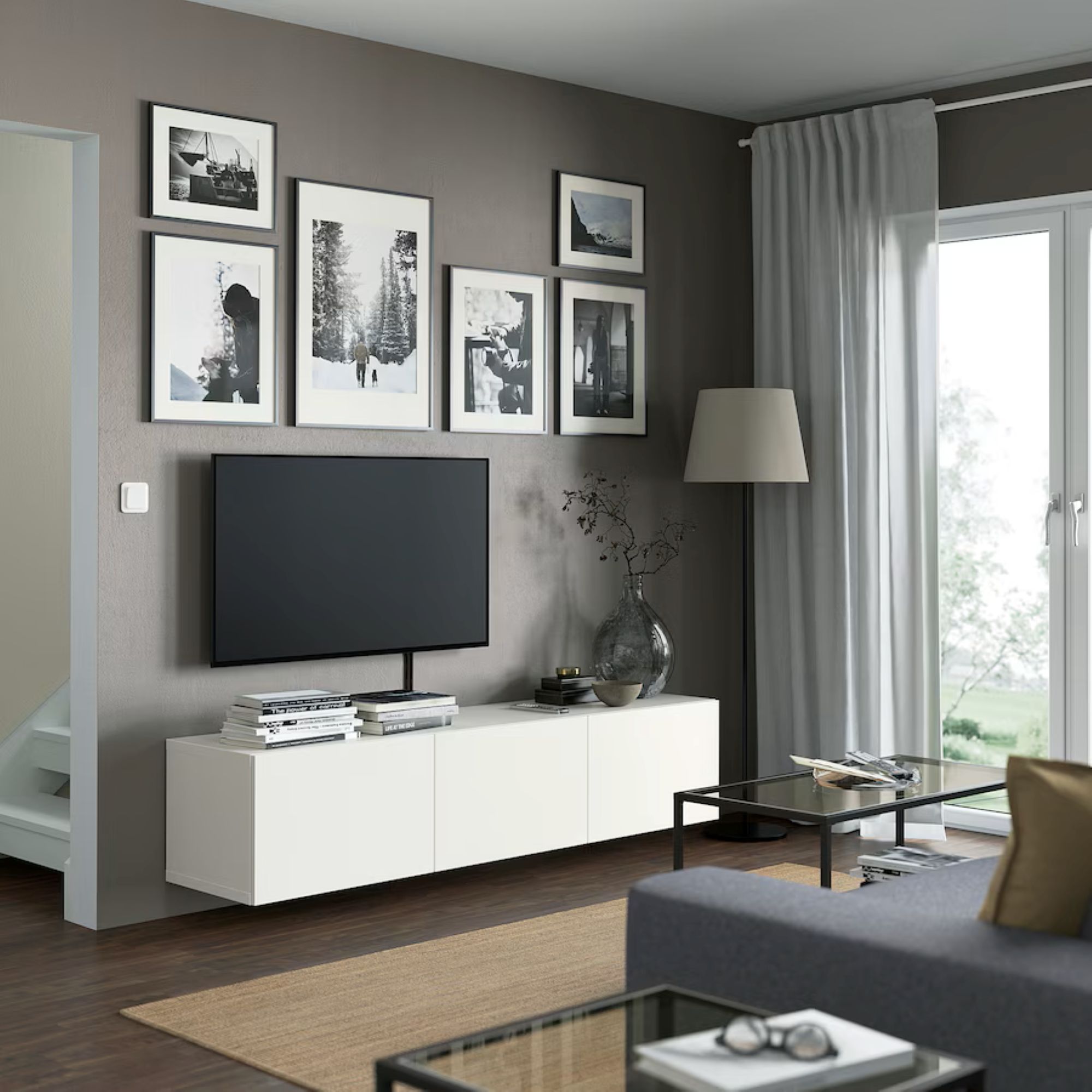 living room with a gallery wall, TV, white TV table and a tan carpet