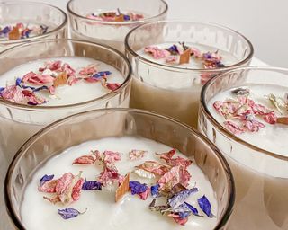 close up of handmade candles in glasses with dried petals