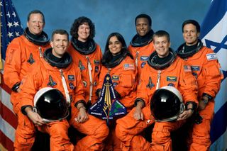 a group of seven NASA astronauts in orange flightsuits