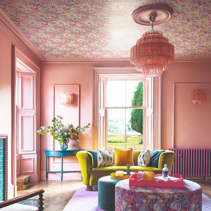 Pink-painted living room with a floral wallpaper-covered ceiling and a statement ceiling light