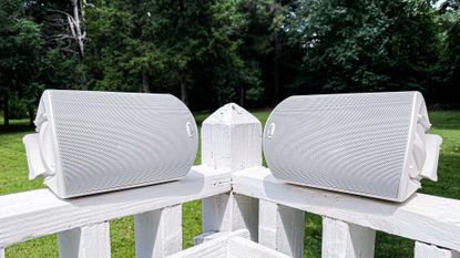 Polk Atrium 4 outdoor speakers on a wooden fence in a sunny garden