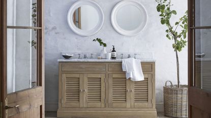 An example of traditional powder room ideas showing a classic, wooden washstand with two sinks below two white wall mirrors