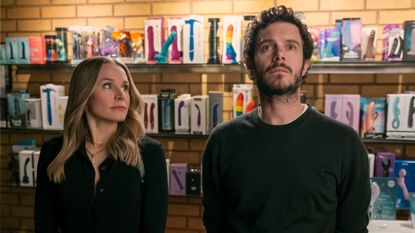 Kristen Bell as Joanne and Adam Brody as Noah, standing in front of a wall of sex toys, in episode 106 of Nobody Wants This.