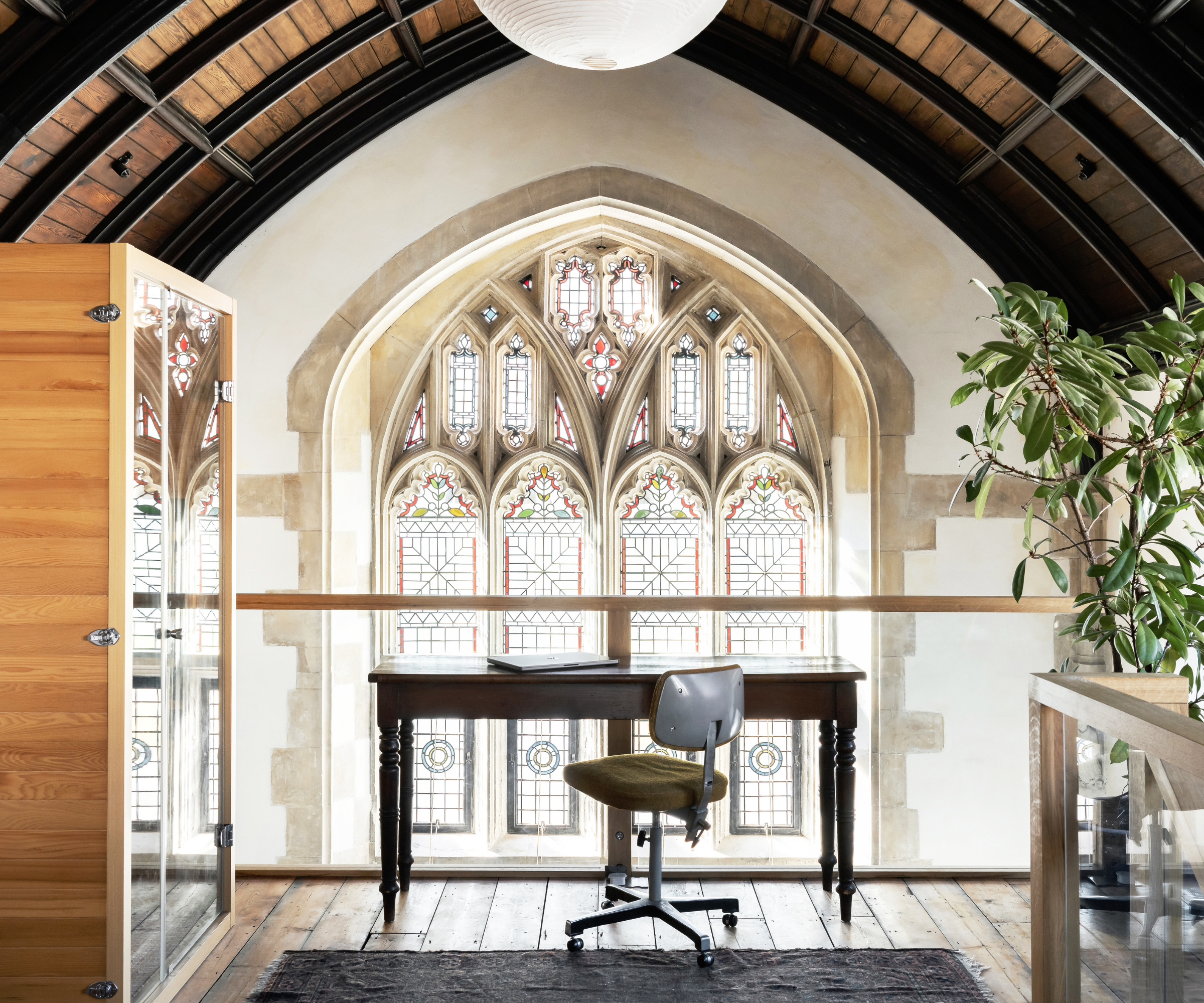Mezzanine top with desk in front of large stained glass window 