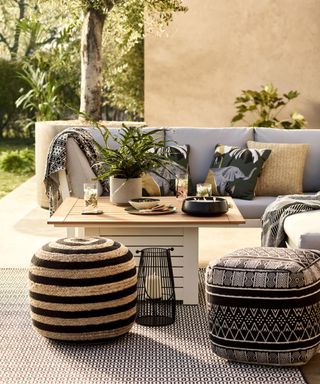A modern boho outdoor living space with outdoor cushions and textured ottoman pouffe