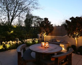 lighting in flower beds and trees around the edge of a patio