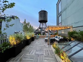 A rooftop garden with garden furniture under a pergola