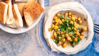 Chickpeas scattered on top of hummus with pita bread
