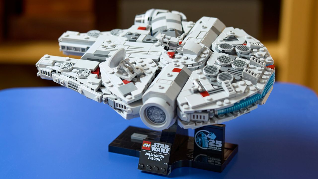 Lego Millennium Falcon model on its stand on a blue table
