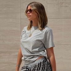 Sofia Richie Grainge wears grey track pants with a grey t-shirt, grey Balenciaga City bag and brown trainers.