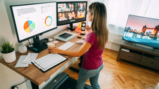 Woman using standing desk with two monitors