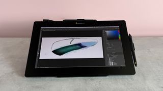 The Xencelabs Pen Display 16 showing a line drawing of a feather featuring green, purple and blue watercolor brushes over the top.