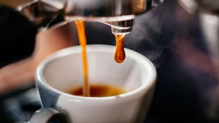 An espresso shot coming out of a machine into a cup