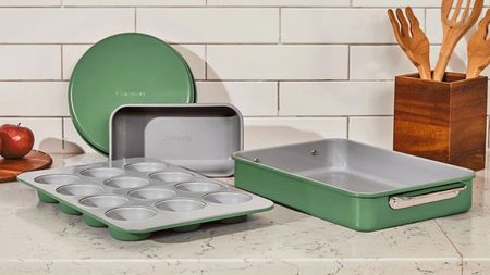 A collection of green and grey bakeware on a marble countertop, with white subway backsplash