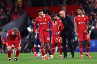 Arne Slot puts his right arm around Darwin Nunez with disconsolate Liverpool players around him following Liverpool's penalty shoot out defeat to PSG in the Champions League