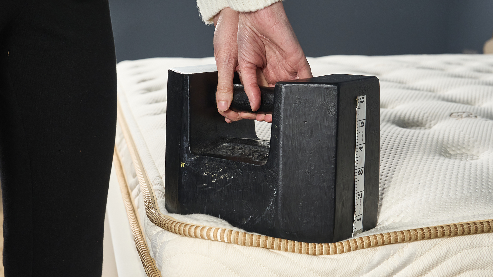 A 25kg black cast iron weight is placed on the corner of the Saatva Classic mattress to test its edge support further