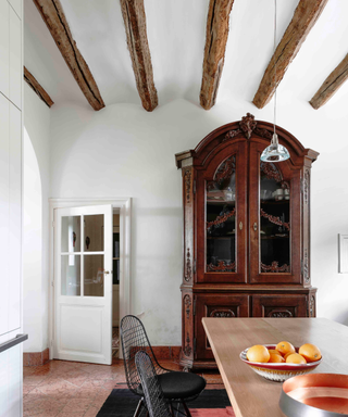 White cottage-style home with imposing mahogany armoire framing wooden dining table