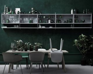 A dining room wall idea with emerald green wall paint and white modular shelving