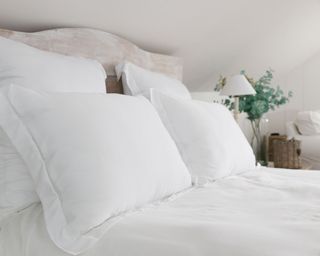 white pillows and bedding with wooden headboard