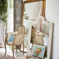 A bedroom with two large mirrors leaning against the wall