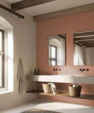 bathroom with earthy pink wall, wood ceiling beams, double minimalist sink and mirrors