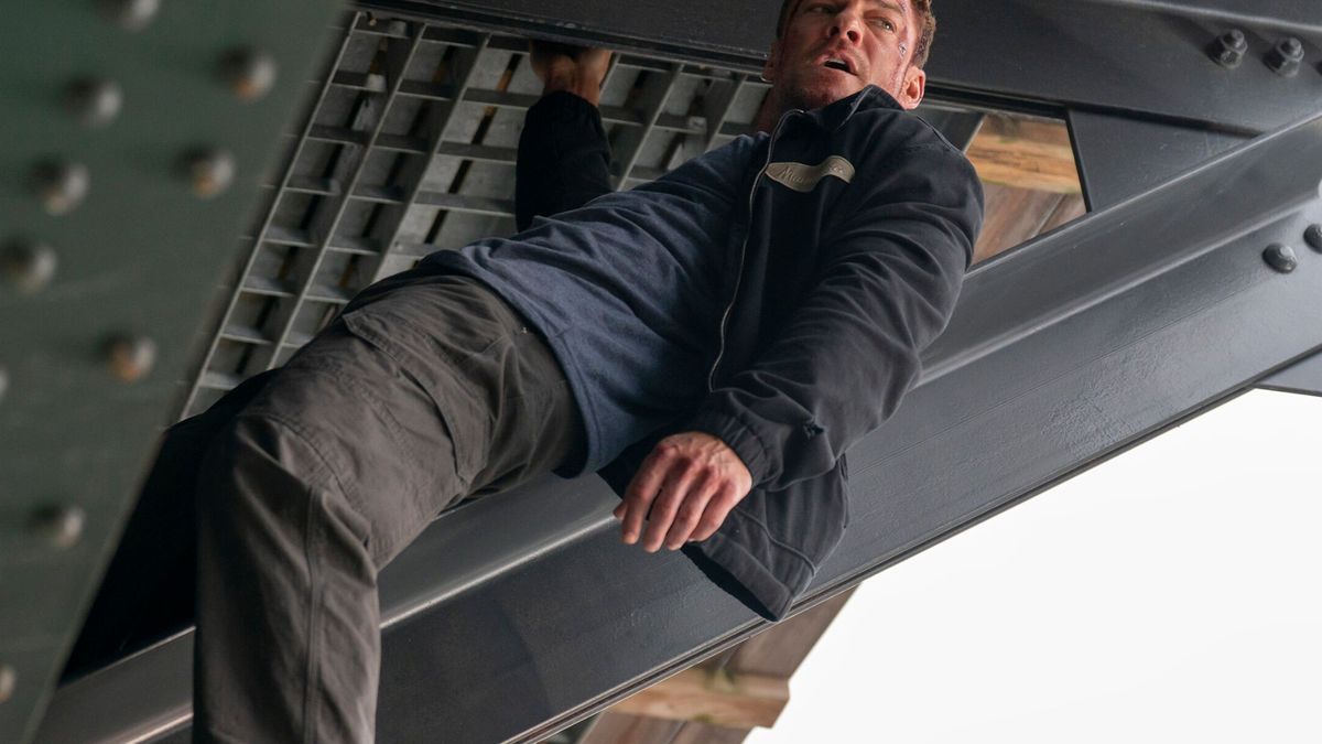 Jack Reacher hangs off of metal scaffolding