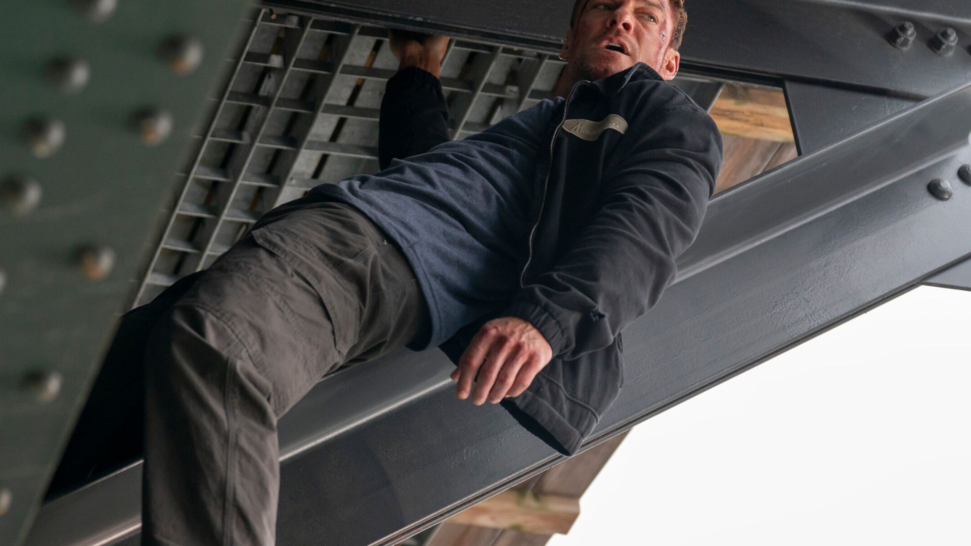 Jack Reacher hangs off of metal scaffolding
