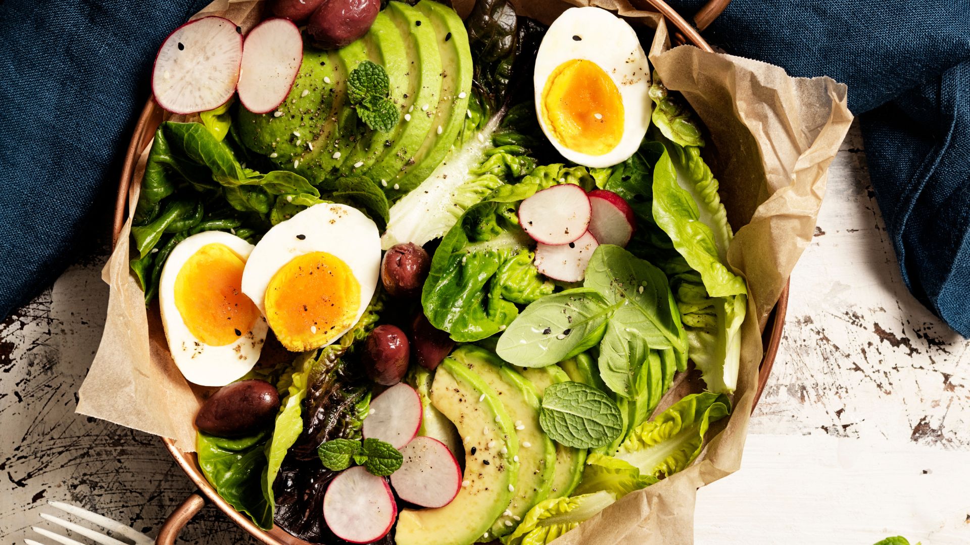 Salad with boiled eggs, avocado, olives and leaves
