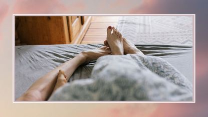 couples feet entangled at the end of the bed, against a pink background
