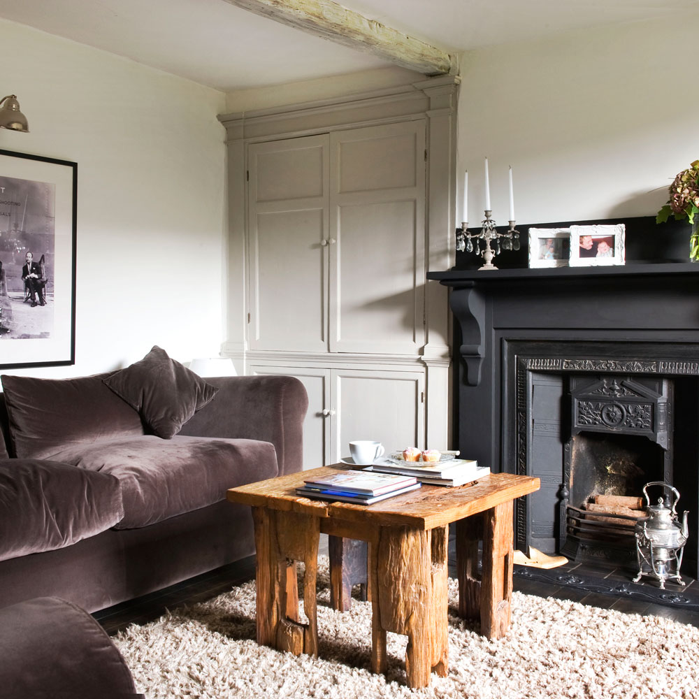 living room with mauve velvet sofa black fireplace and wooden coffee table