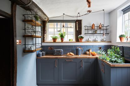 navy kitchen cabinetry with industrial style open shelving and lighting