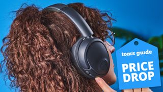 the jlab jbuds lux anc headphones worn by the author with a tom's guide price drop tag