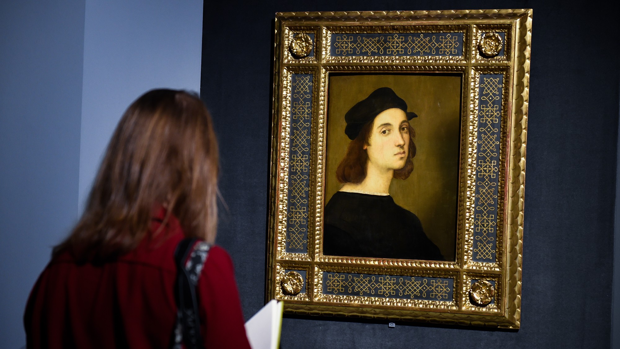 A woman in Rome looks at a self-portrait by Raphael