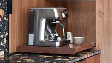 coffee niche with wooden cabinetry, terrazzo countertops, and a chrome coffee machine